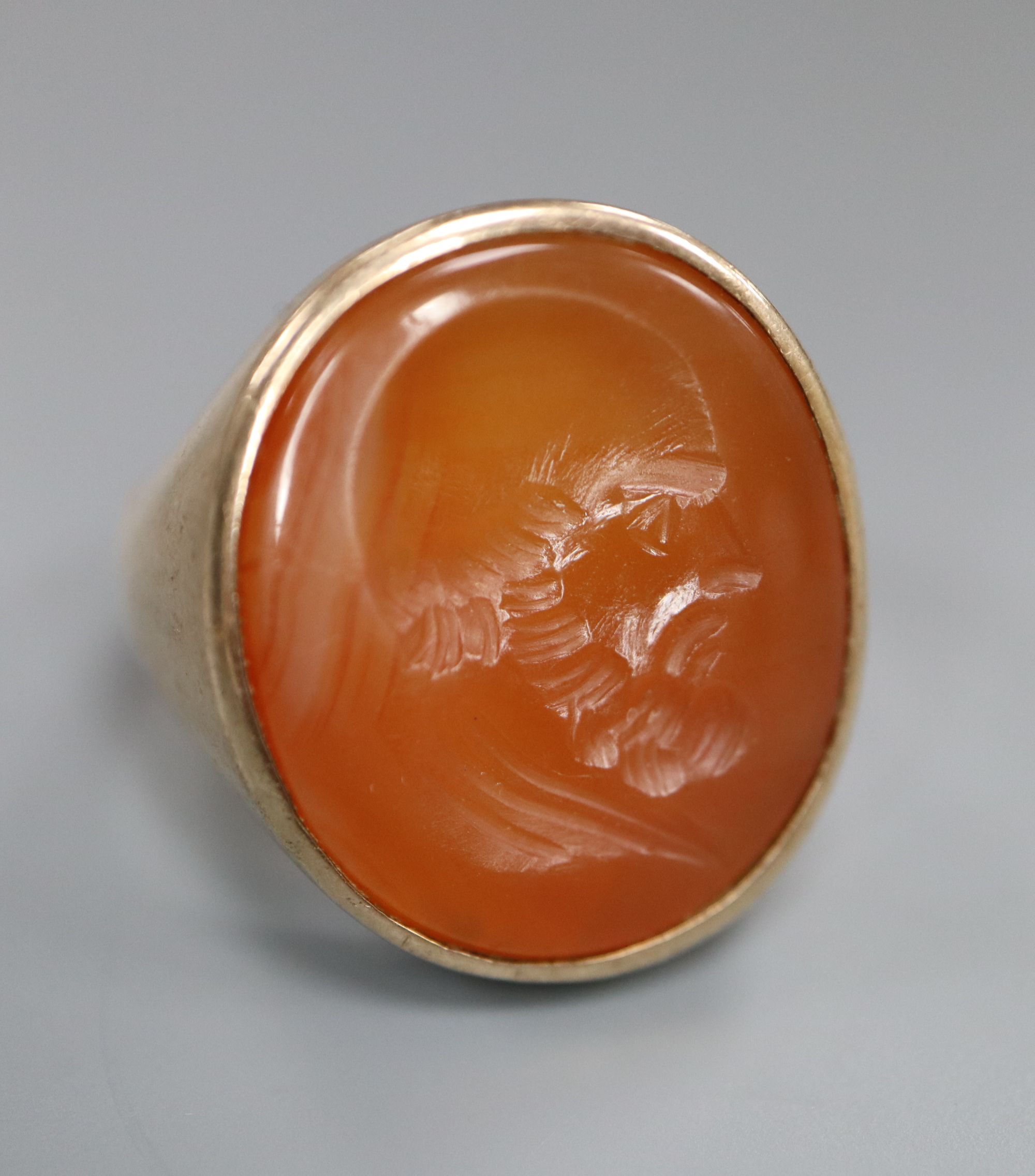 A late 19th century yellow metal and oval carnelian intaglio ring, carved with the head of a gentleman to sinister, size R,